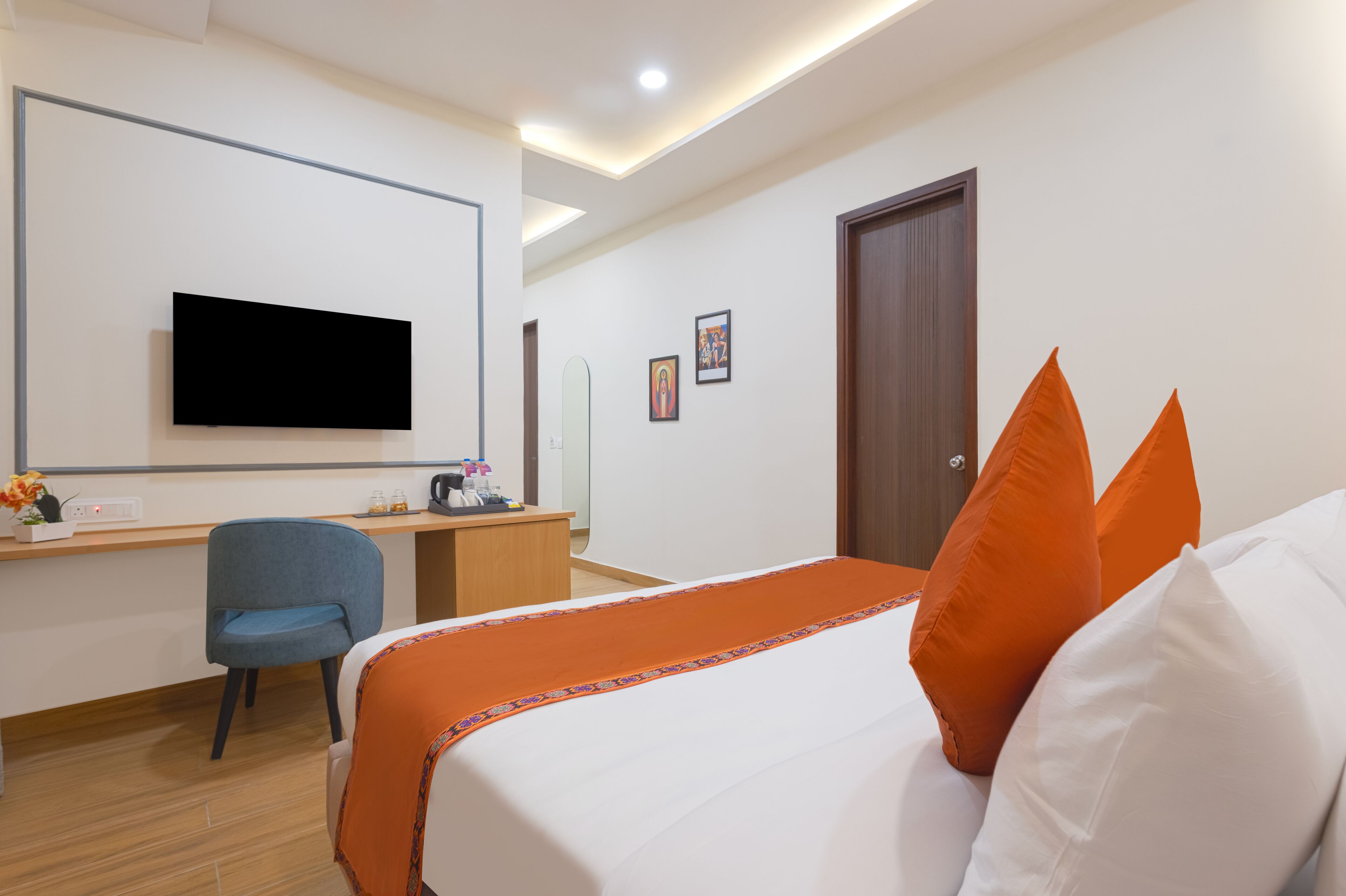 A hotel room with a bed, a desk, a chair, a television, and a door.