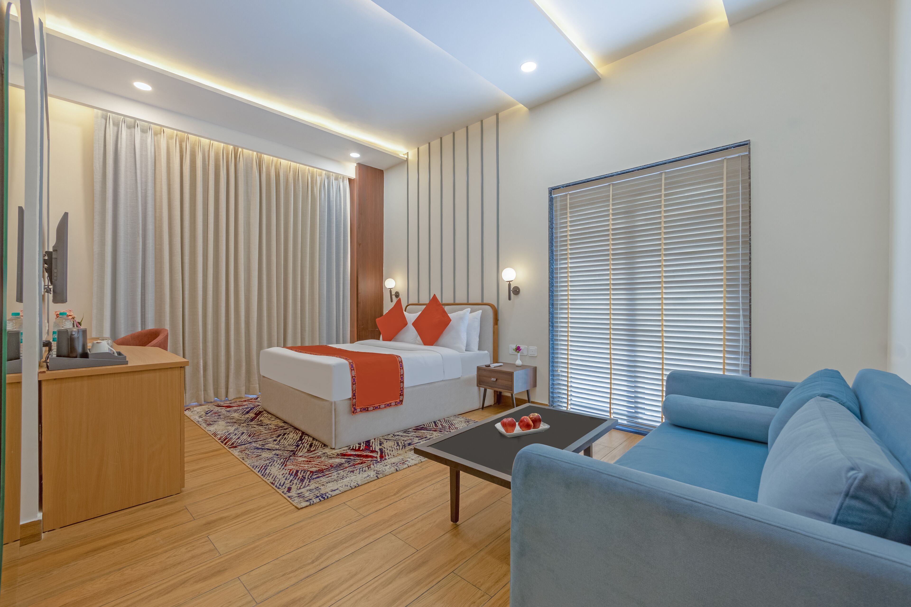 Una habitación de hotel moderna con una cama, un sofá, un escritorio y una ventana con persianas.