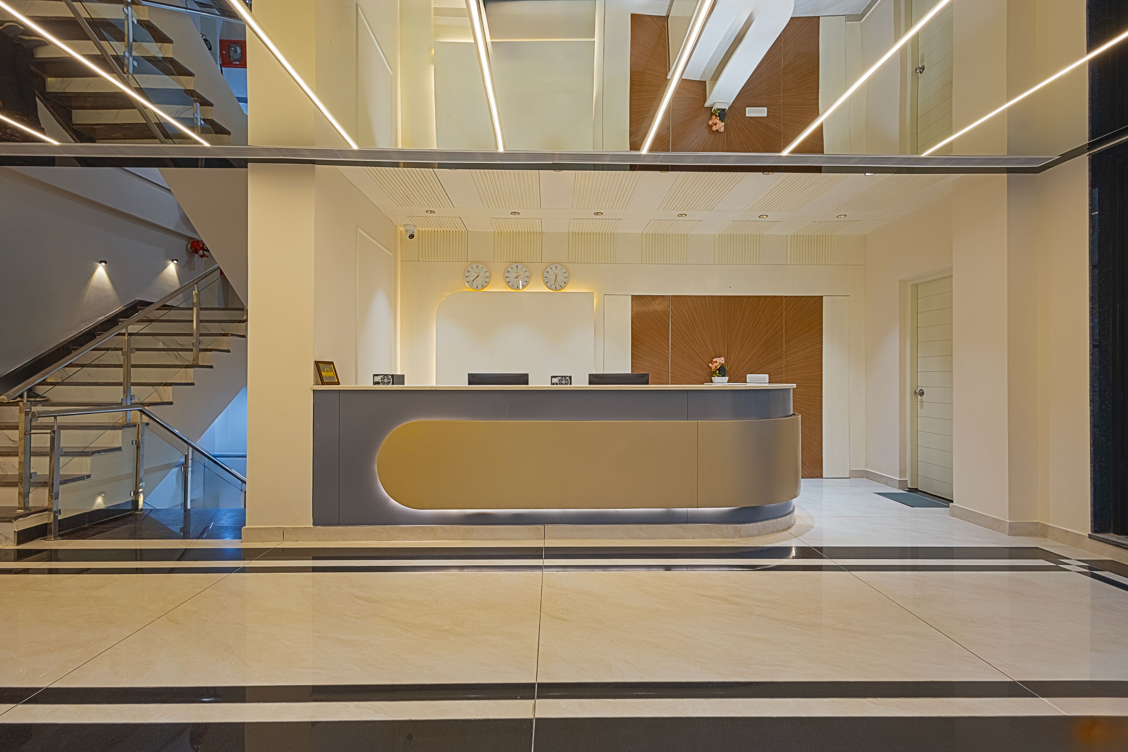 A modern reception area with a curved desk, a staircase, and a wooden accent wall.