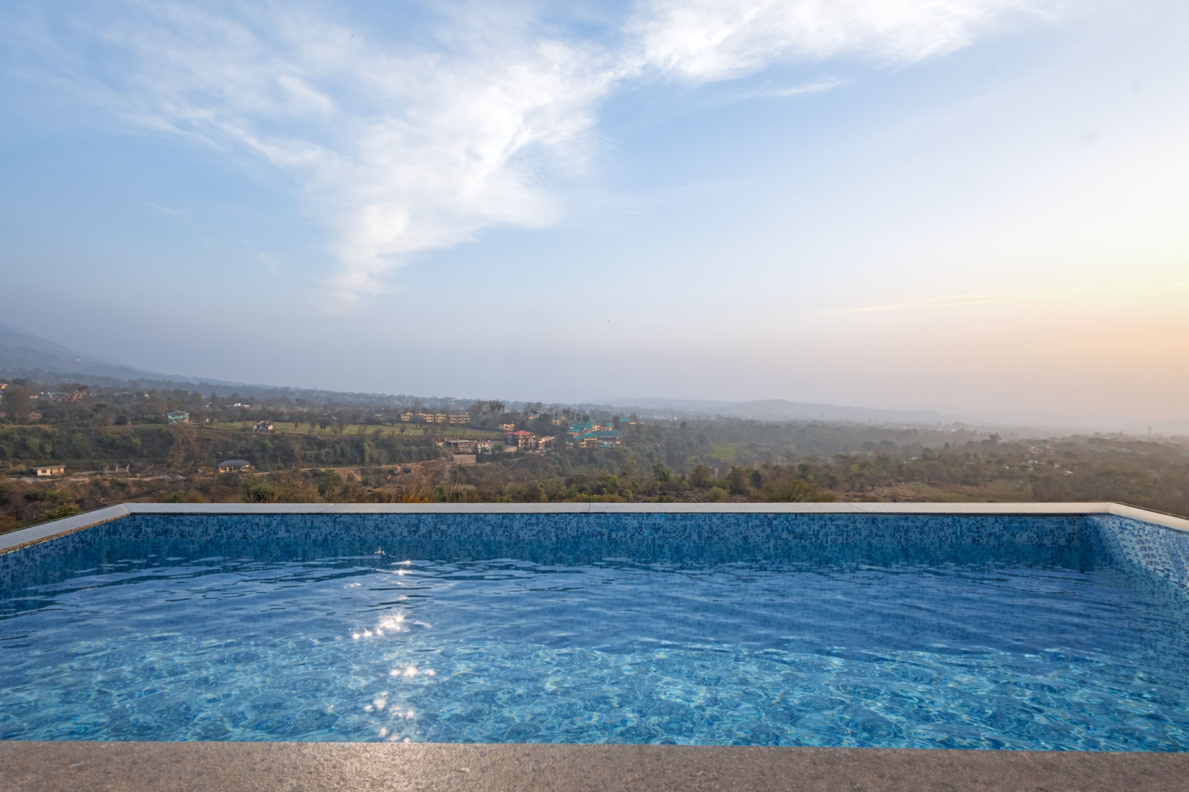 A swimming pool with a clear view of a distant landscape and mountains.