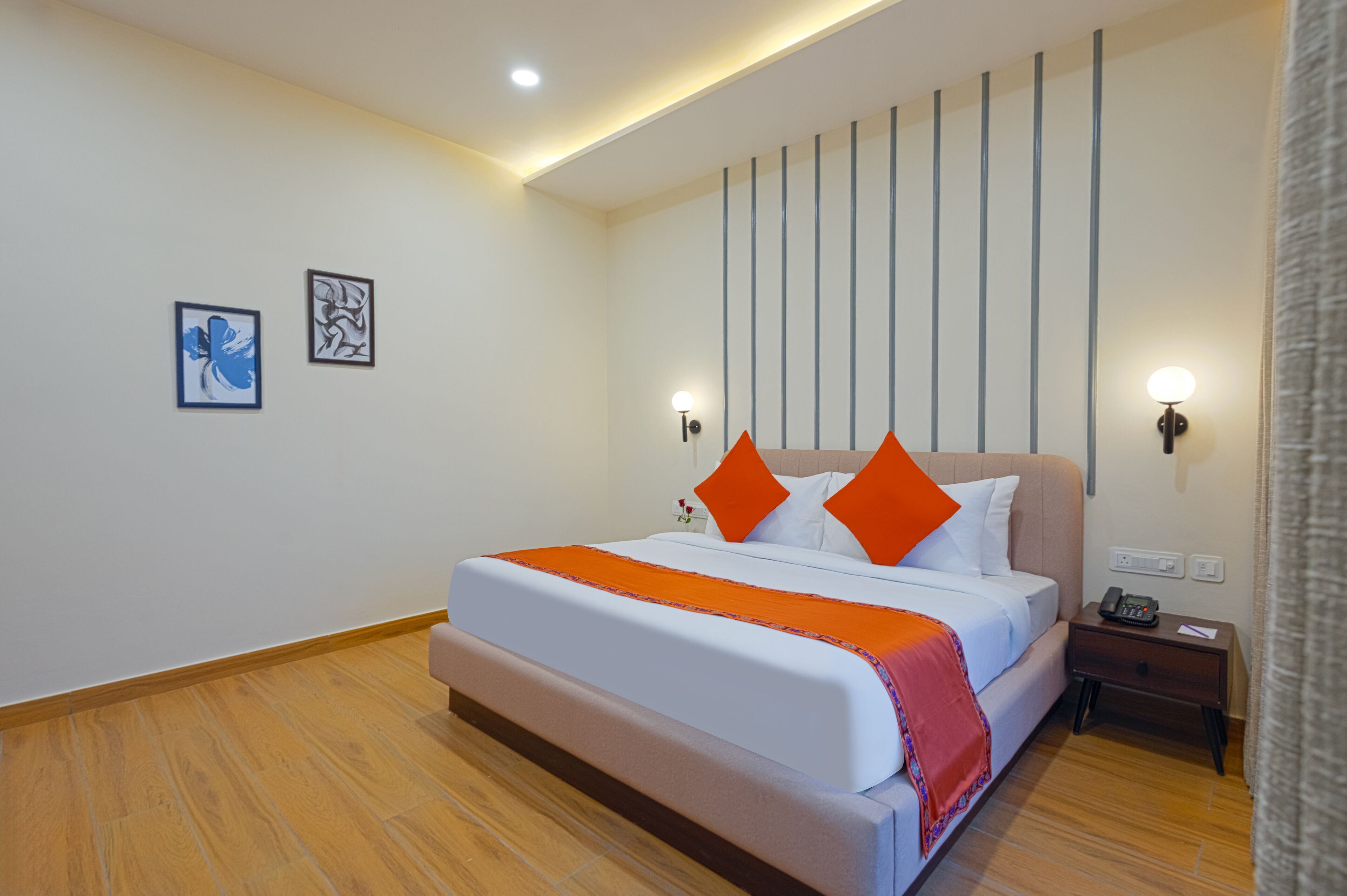 A hotel room with a large bed, a nightstand with a phone, and two wall-mounted lights.