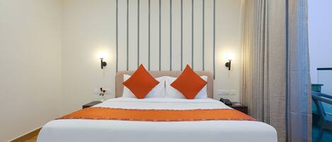 A hotel room with a large bed, two nightstands, a wall-mounted light, and a view of the balcony.