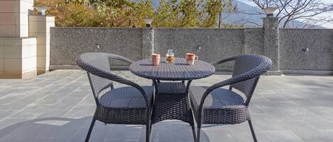 A patio with wicker chairs and a table, a water feature, and a view of snow-capped mountains.