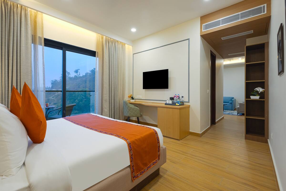 Een hotelkamer met een groot bed, een bureau, een televisie en uitzicht op het buiten.