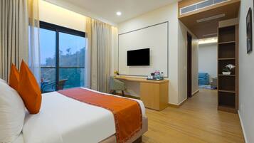 A hotel room with a large bed, a desk, a television, and a view of the outdoors.