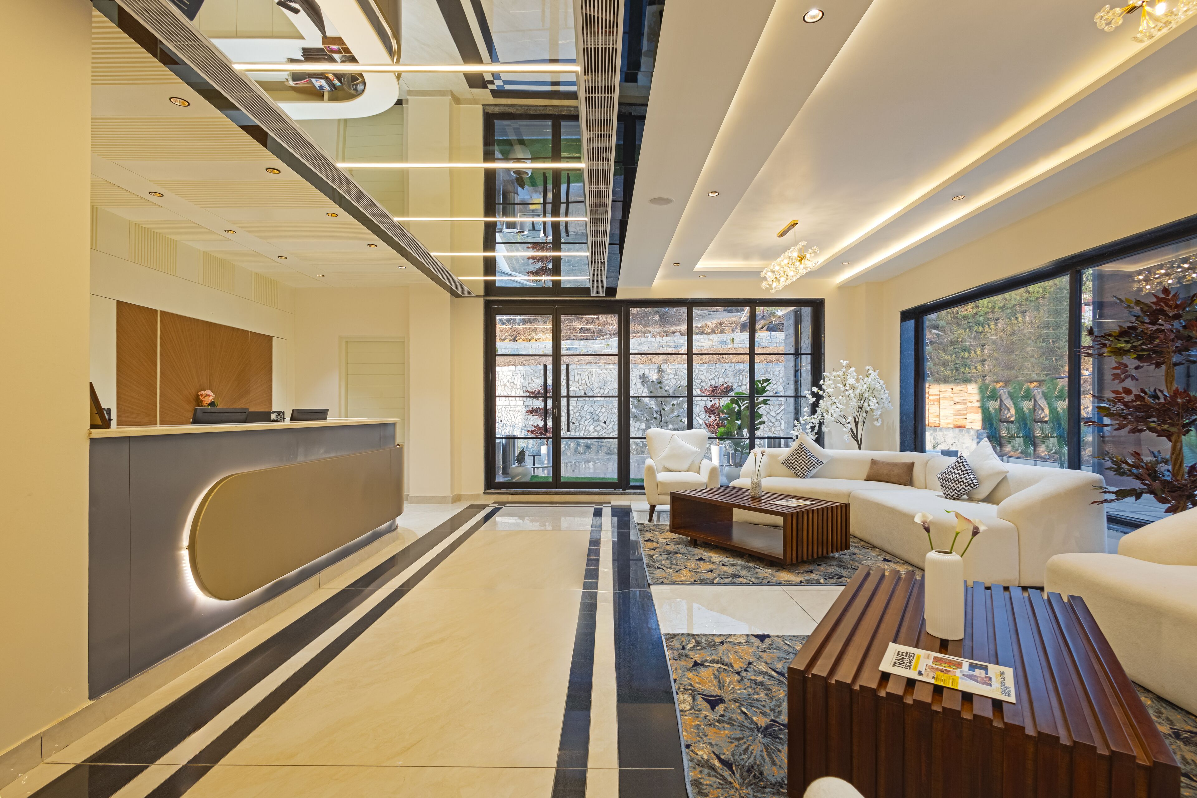 A modern hotel lobby with a reception desk, seating area, and large windows offering views of the outdoors.