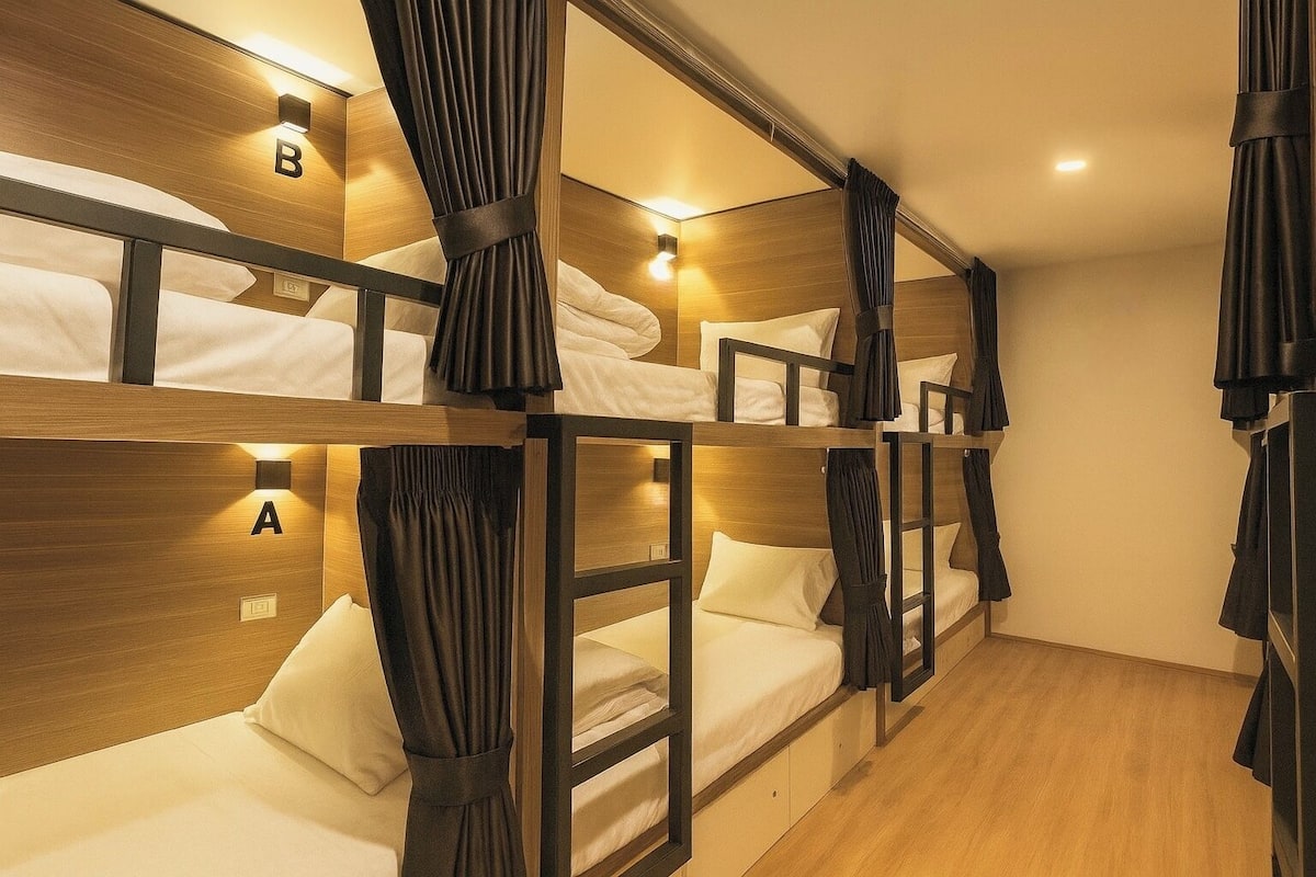 A room with bunk beds, each labeled with a letter, and a wooden floor.