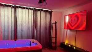 A room with a massage table, a wall-mounted TV, a ladder, and a bench. - Émoi de Toi – Love Room Prestige, Private Jacuzzi, Breakfast (Sigean)