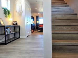 Ein Flur mit einer Holztreppe, einem Bücherregal und einem Traumfänger an der Wand.