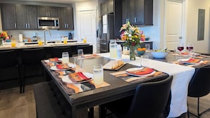 Une cuisine moderne avec des meubles de couleur sombre, un îlot central et un coin repas aménagé pour prendre un repas.