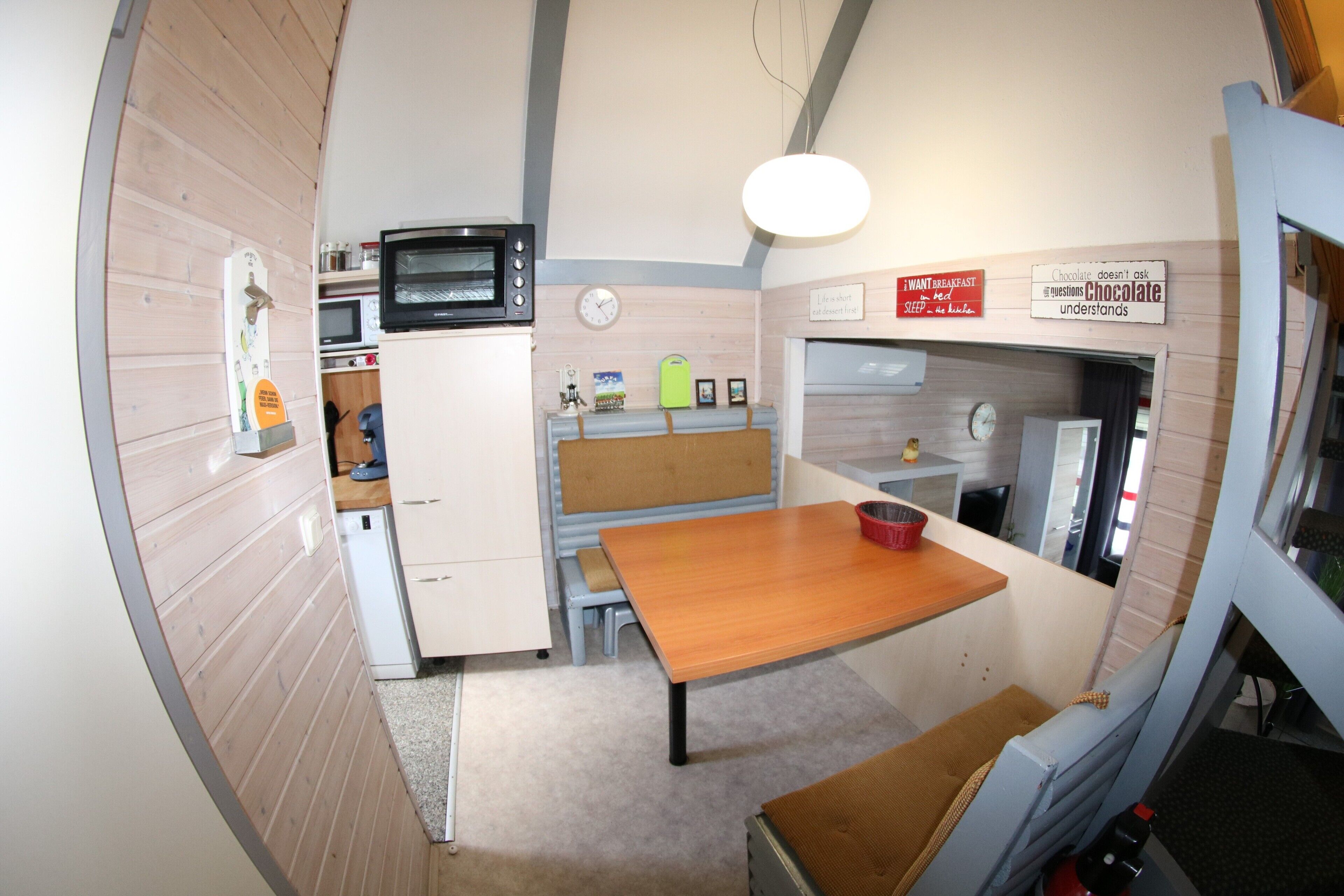A compact kitchen with a microwave, oven, and a wooden table.