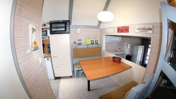 A compact kitchen with a microwave, oven, and a wooden table.