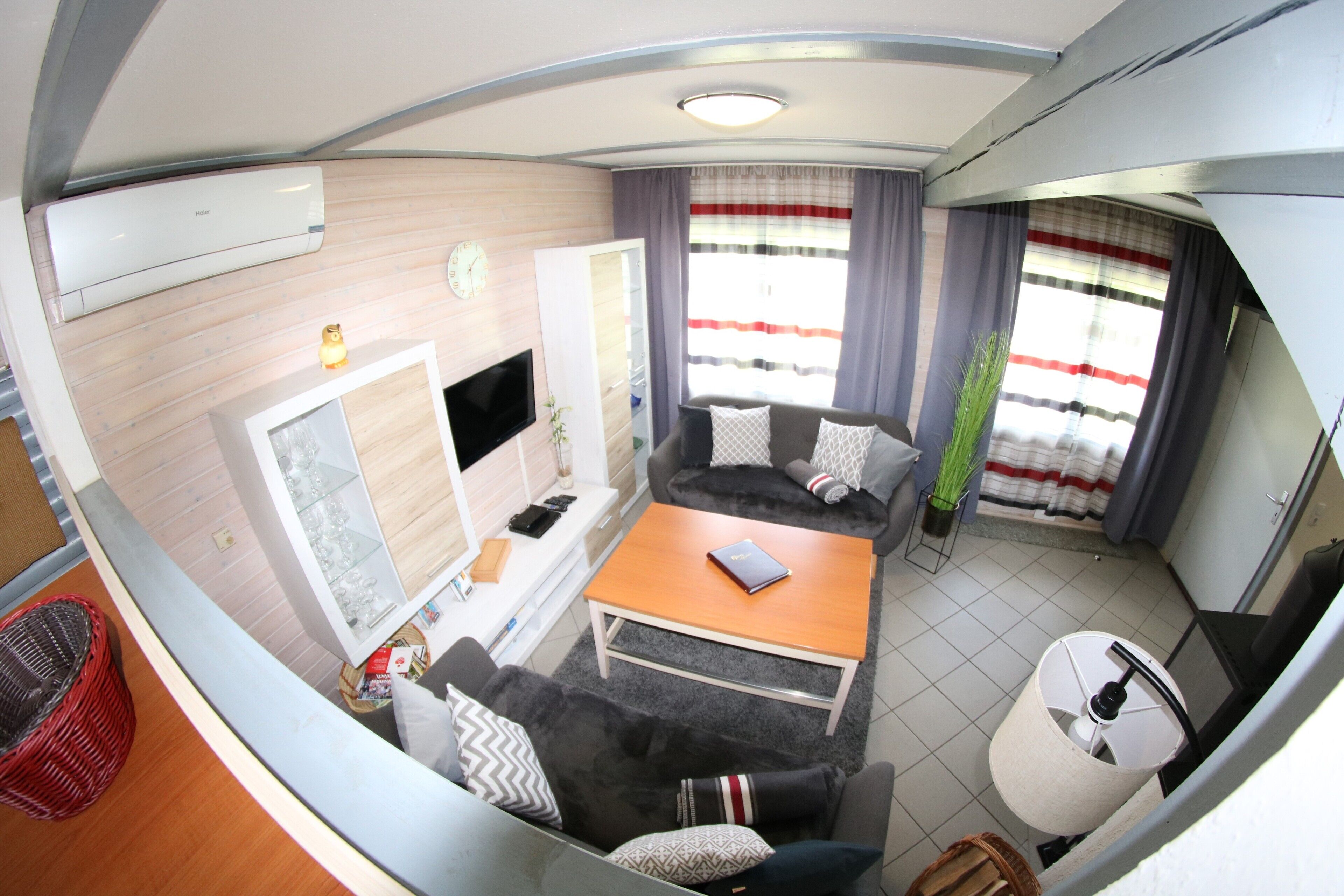 Un espace de vie compact comprenant un canapé, une table basse, un téléviseur à écran plat et une petite table à manger.