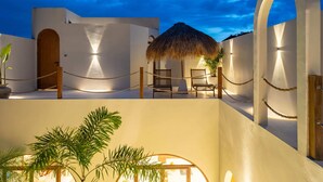 Un hôtel moderne doté d’un espace extérieur avec des sièges et un toit de chaume, de murs blancs et d’une barrière faite de cordes.