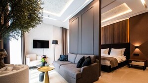Ein modernes Hotelzimmer mit Sofa, Bett, Fernseher und einem großen Baum.