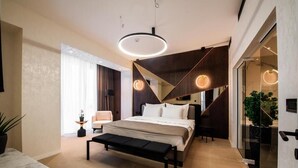Ein modernes Schlafzimmer mit einem großen Bett, Nachttischen, einer Bank und einer runden Leuchte.