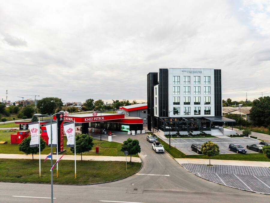 A hotel with a modern design, a parking lot, and a nearby gas station.