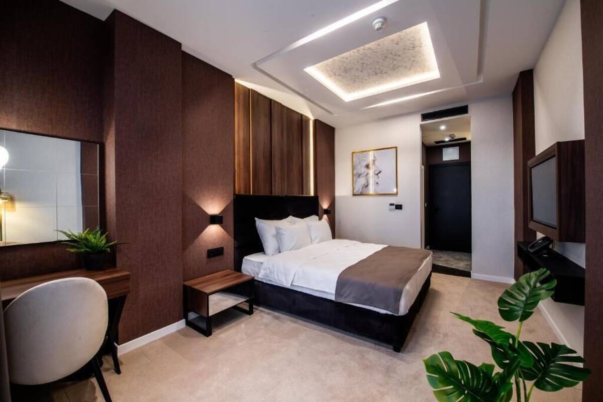 A modern bedroom with a large bed, bedside tables, a desk, and a TV.