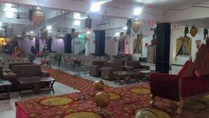 Un salón amplio con filas de sillas y mesas, elementos decorativos colgantes y una alfombra estampada.