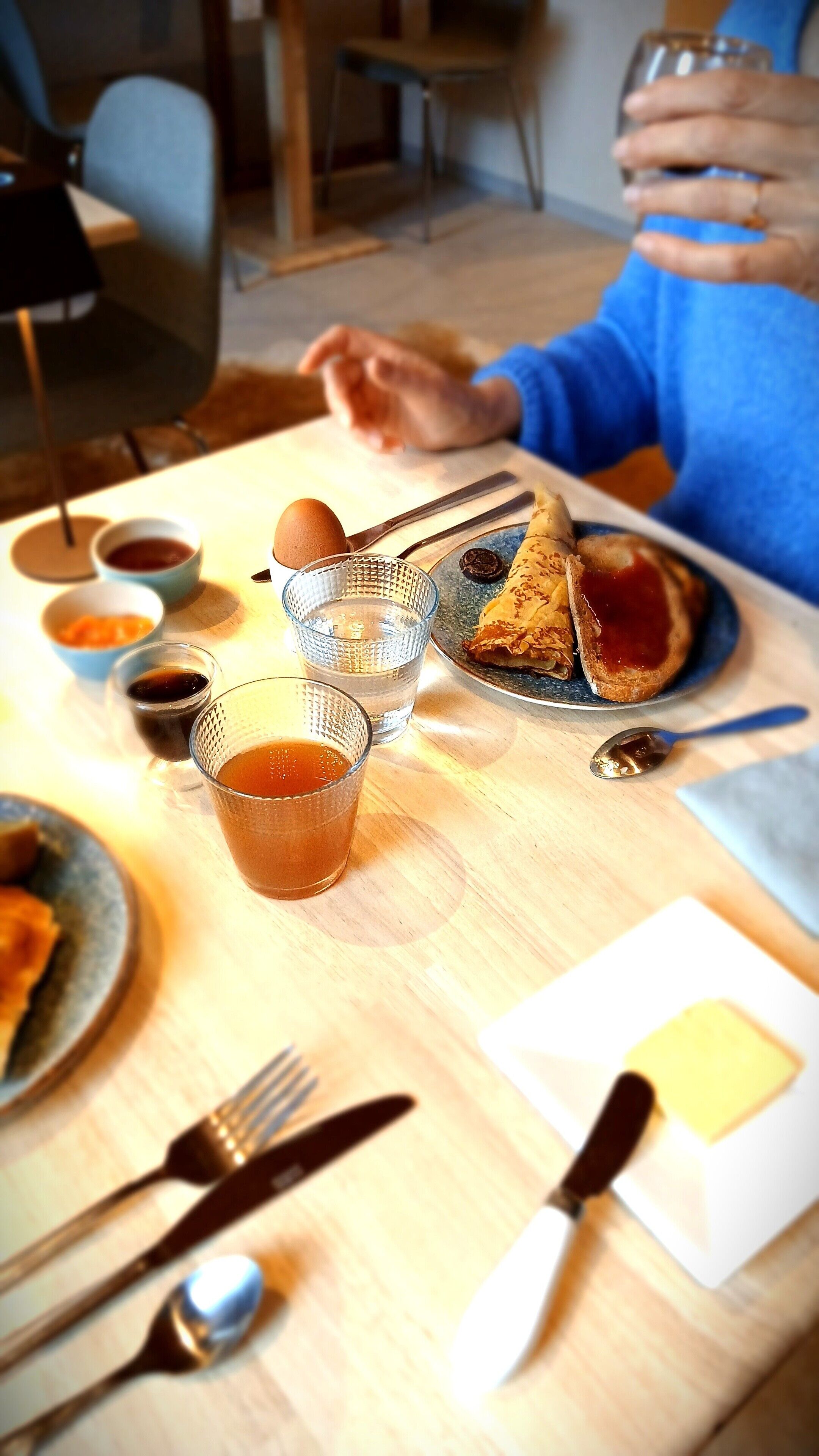 Una mesa de comedor con una tostada, una taza de té y diferentes condimentos.