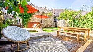 Eine Holzterrasse mit Schaukelstuhl, Bank und kariertem Teppich.
