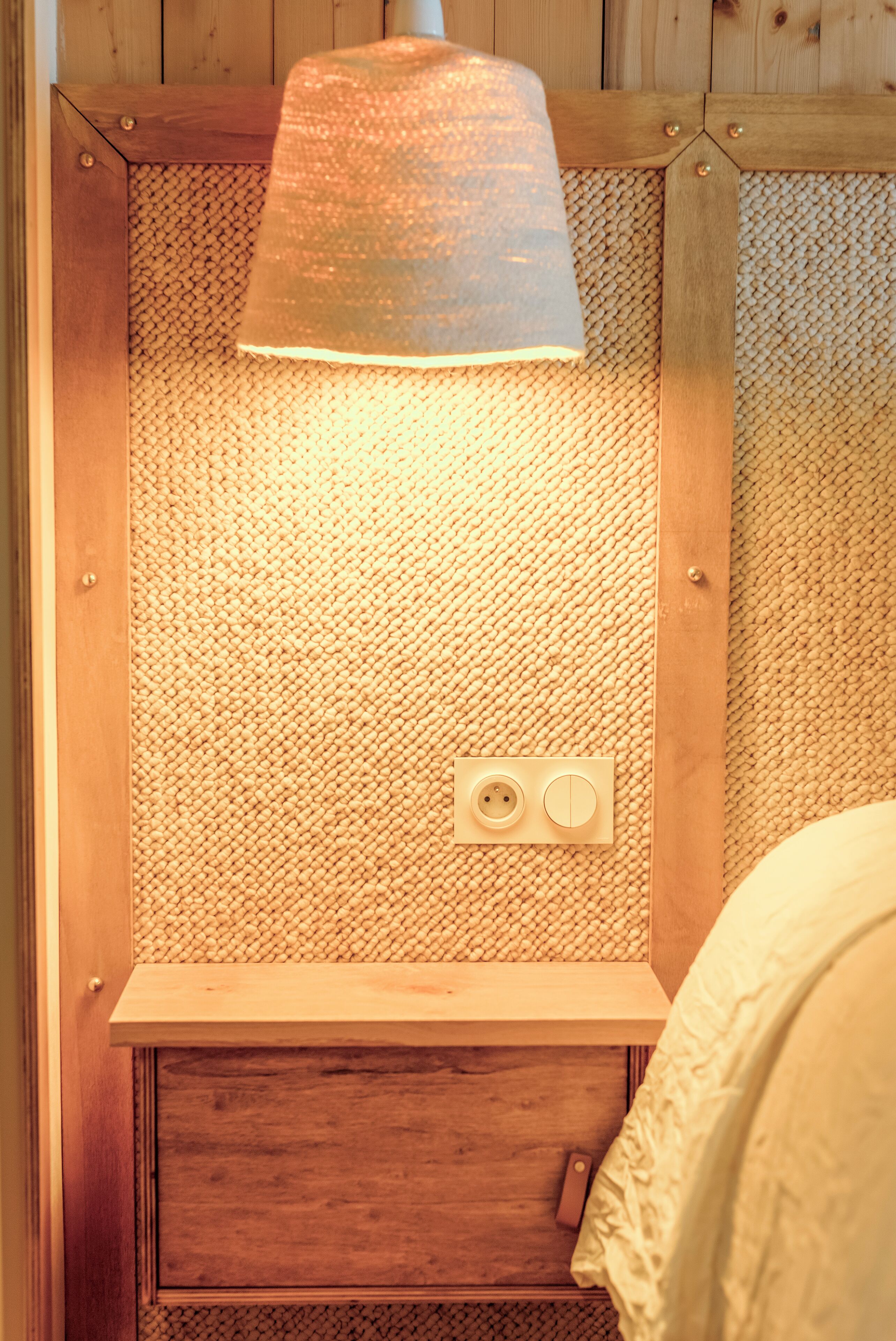 Ein Holzkabinent mit strukturierter Wand und einer Leuchte darüber.