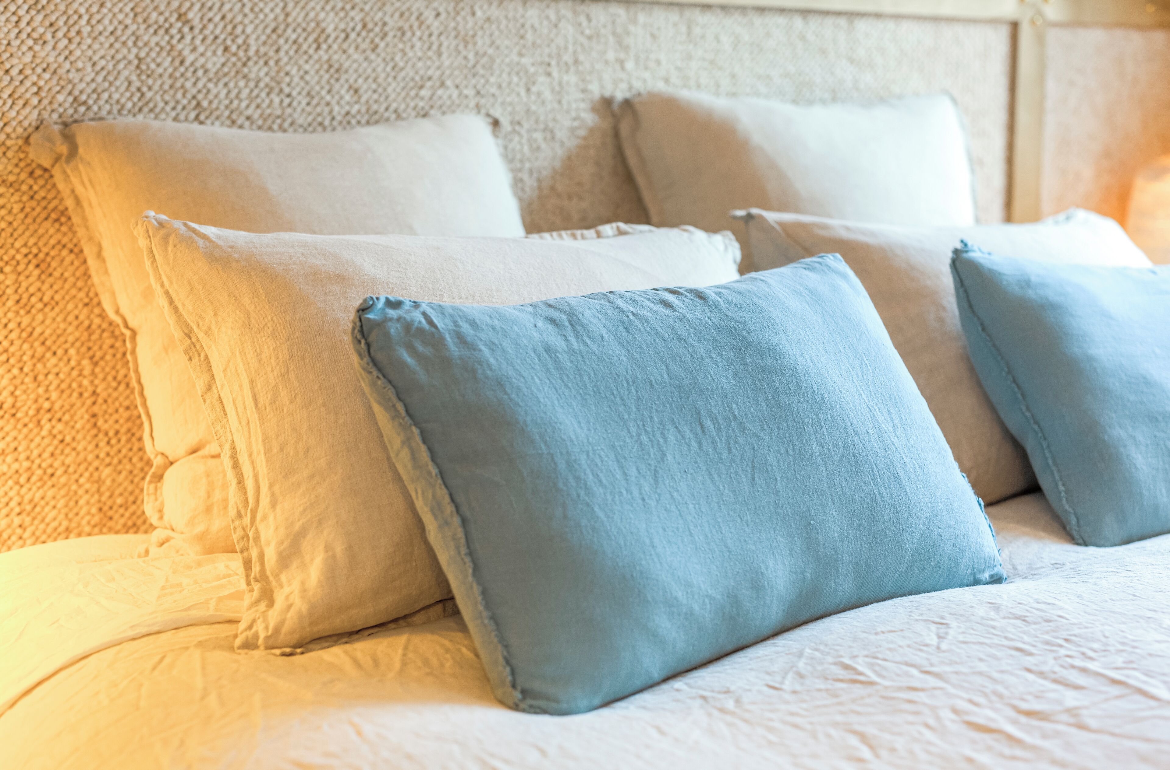 Ein Bett mit mehreren Kissen und einem strukturierten Kopfteil.