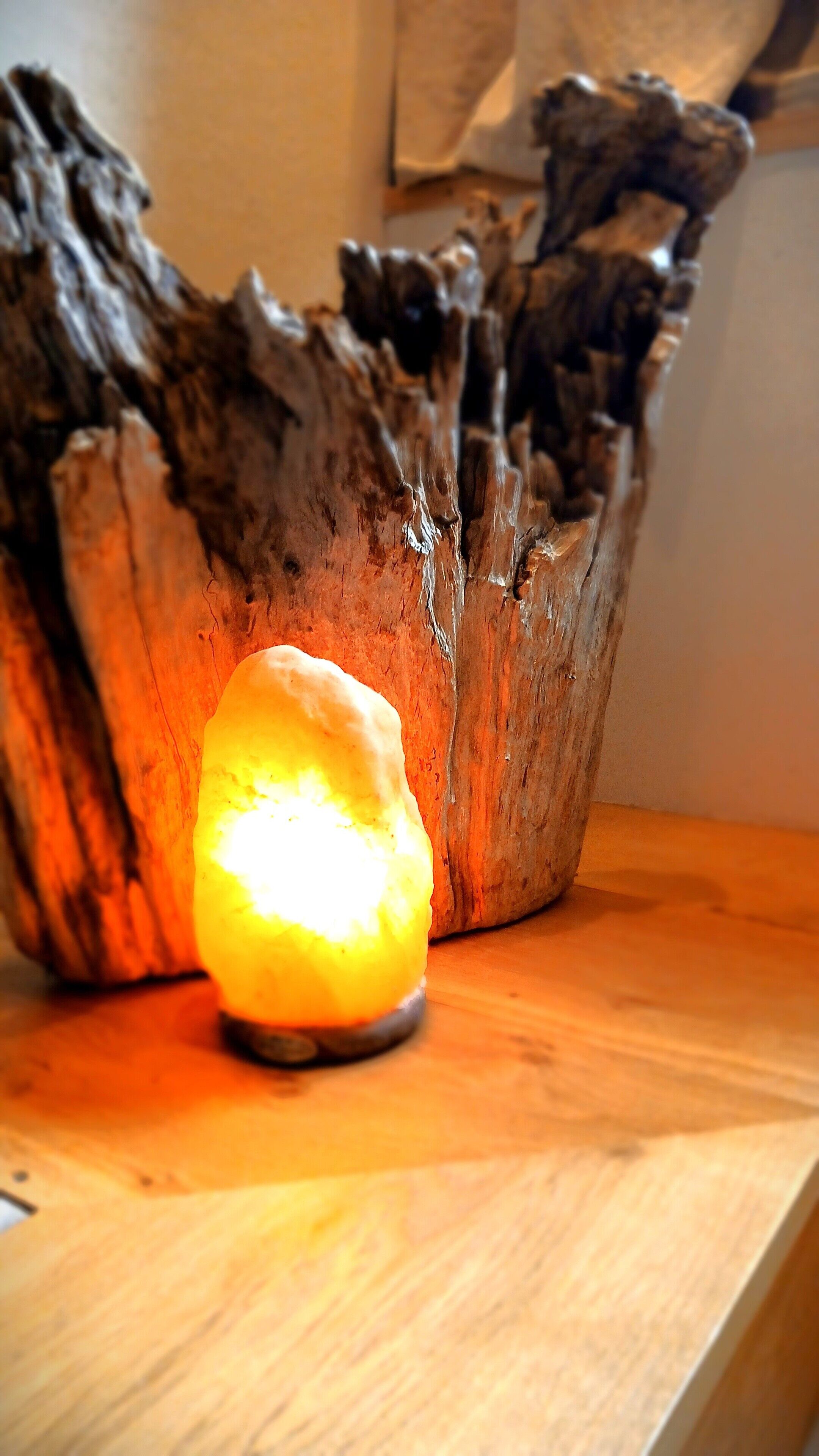 A salt lamp with a rough, textured wooden base.