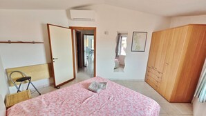 Een slaapkamer met een bed, een kledingkast, een stoel en een deur naar een andere kamer.