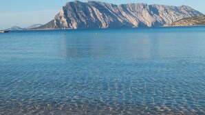 Een helder uitzicht op een grote berg met een rustige zee op de voorgrond.