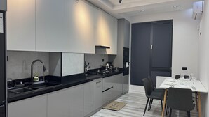 Una cocina moderna con armarios grises, encimera negra y un comedor con mesa y sillas.