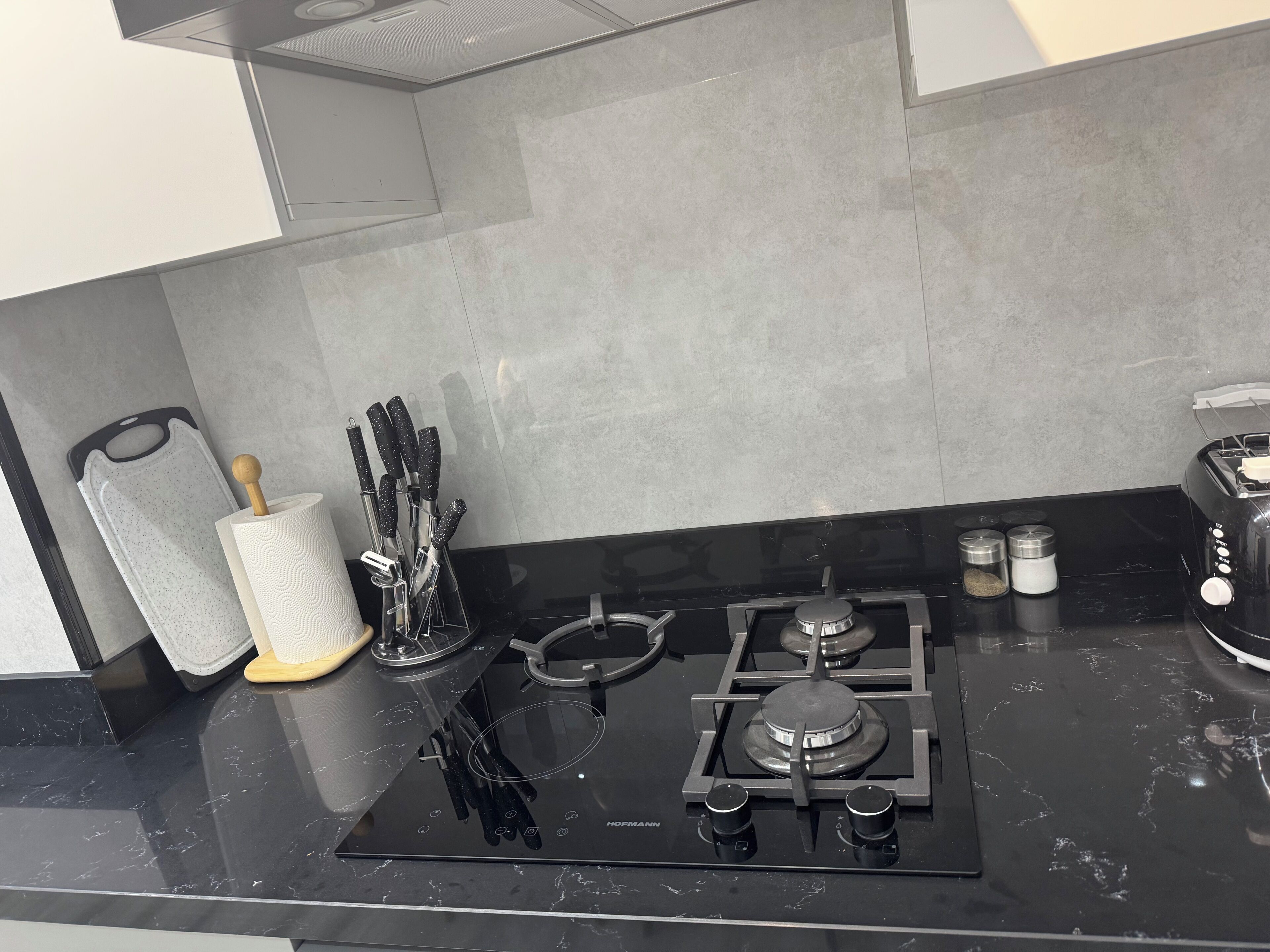 A kitchen with a black stove, a spatula, a rolling pin, and a set of knives.