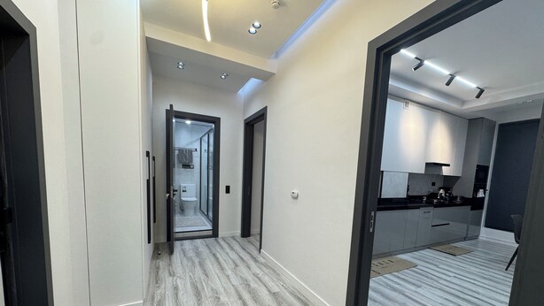 Un interior moderno con un pasillo que conduce a un baño y una zona de cocina.
