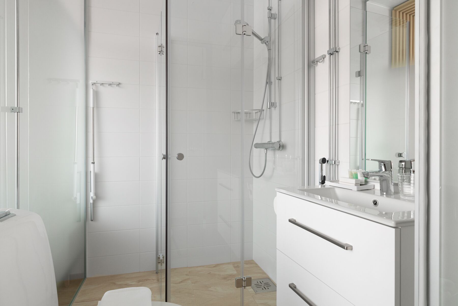 A modern bathroom with a glass shower enclosure, a white vanity with a mirror, and a toilet.