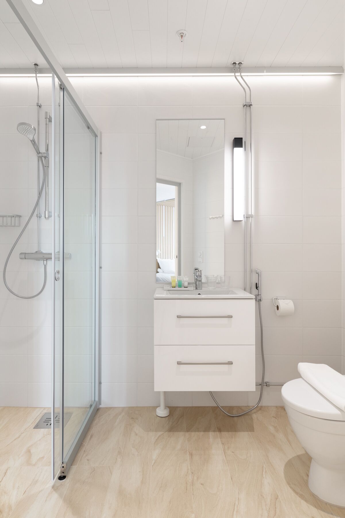 Une salle de bain moderne avec une douche à parois de verre, un meuble-lavabo blanc avec un miroir et des toilettes.