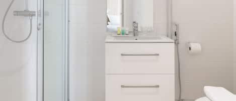 Une salle de bain moderne avec une douche à parois de verre, un meuble-lavabo blanc avec un miroir et des toilettes.