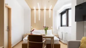A modern hotel room with a bed, a desk, a chair, and a TV. - Polar Nook Hotel (Rovaniemi)