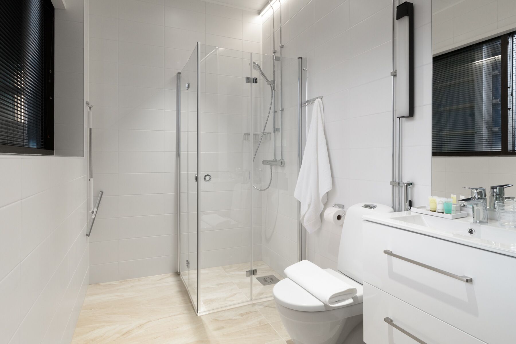 A modern bathroom with a glass shower enclosure, a toilet, and a vanity with a mirror and sink.