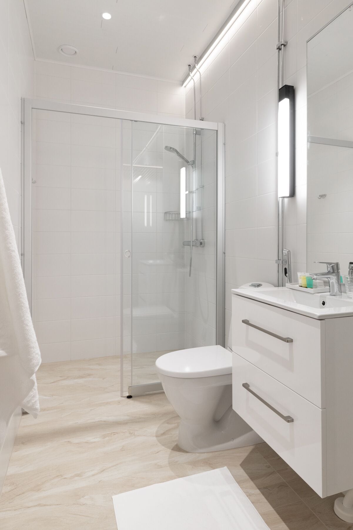 Un baño moderno con ducha de vidrio, inodoro blanco y tocador con espejo.