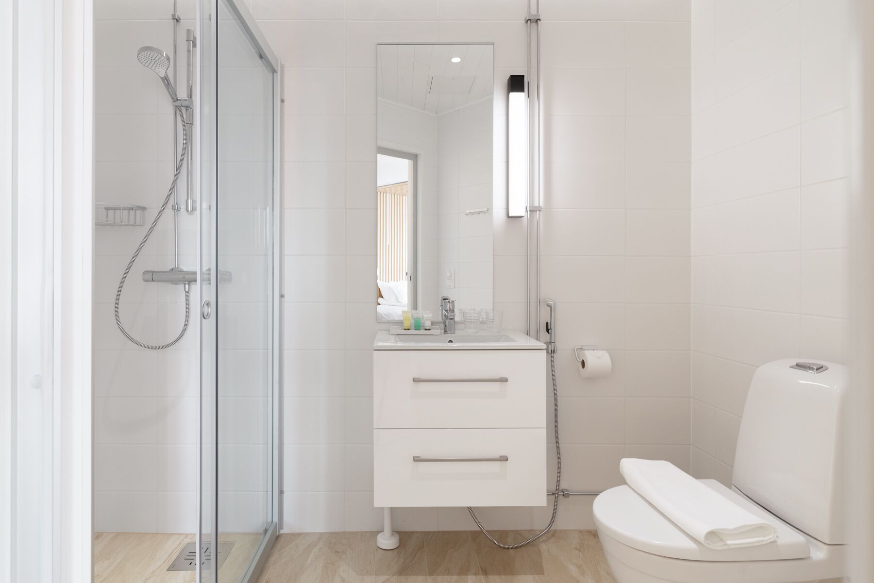 Ein modernes Badezimmer mit einer Duschkabine, einem weißen Waschbecken mit Spiegel und einer Toilette.