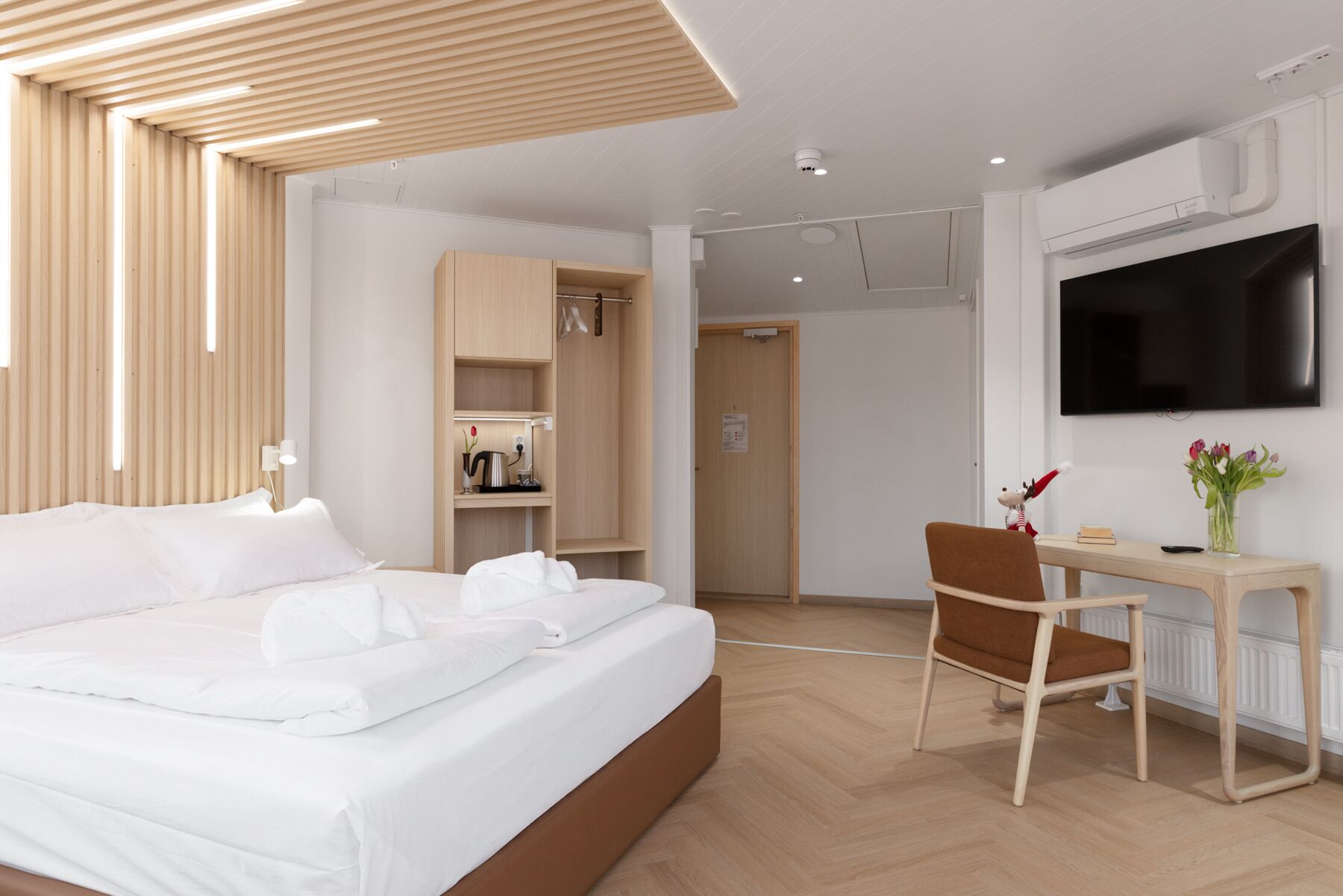Een hotelkamer met een bed, een bureau, een stoel, een televisie en een kledingkast.