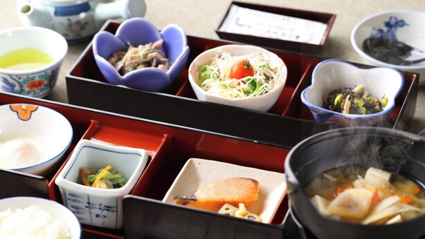 A traditional Japanese meal setup with various dishes in separate compartments, including a bowl of rice, a dish of salmon, and a pot of soup. - Yamano Takohei (Azumino)