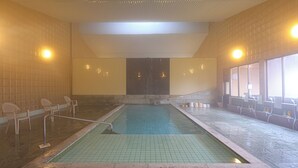 An indoor swimming pool with tiled walls and benches along the sides. - Yamano Takohei (Azumino)