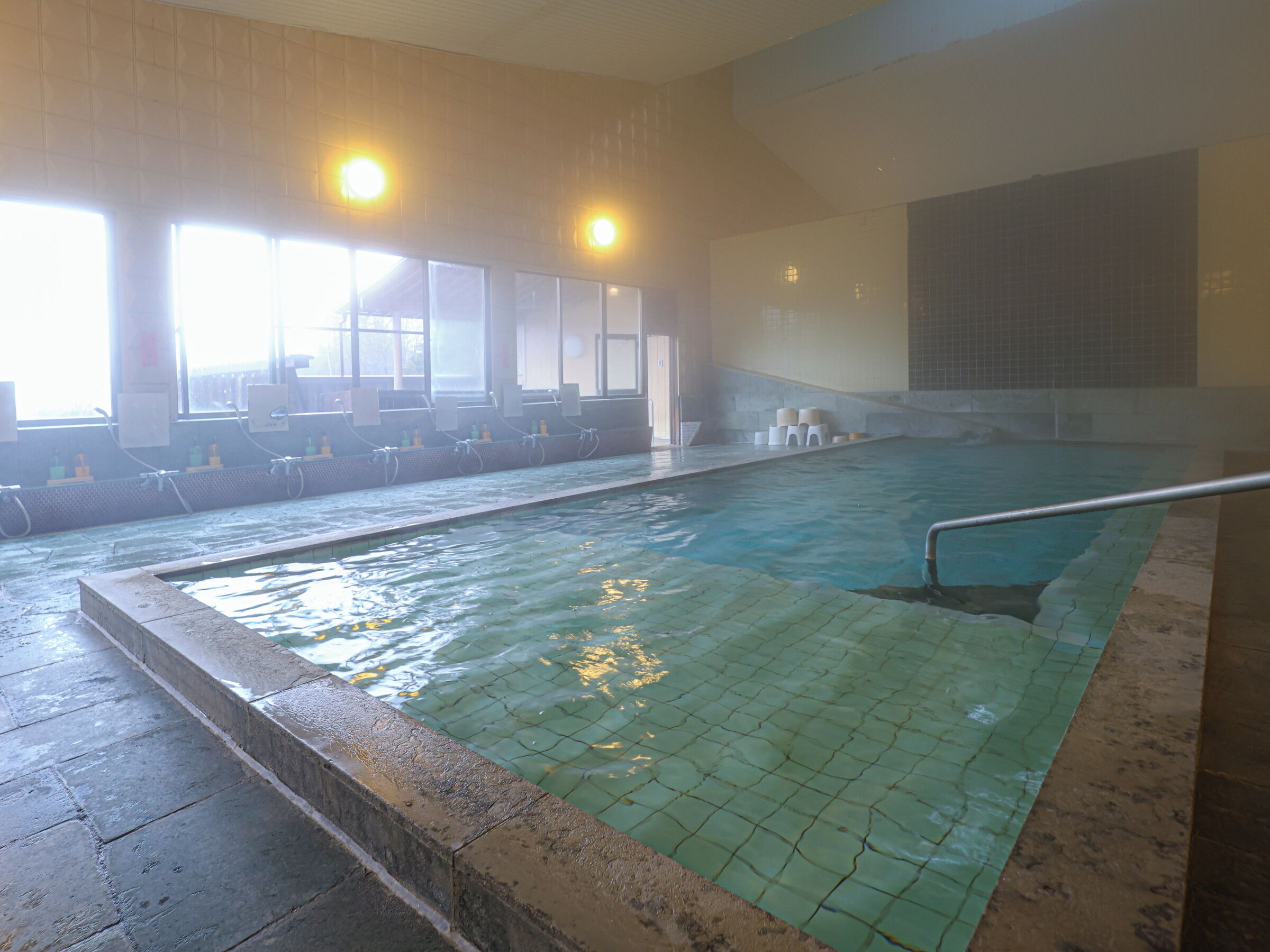 Piscina interna com paredes azulejadas e superfície de água cristalina.