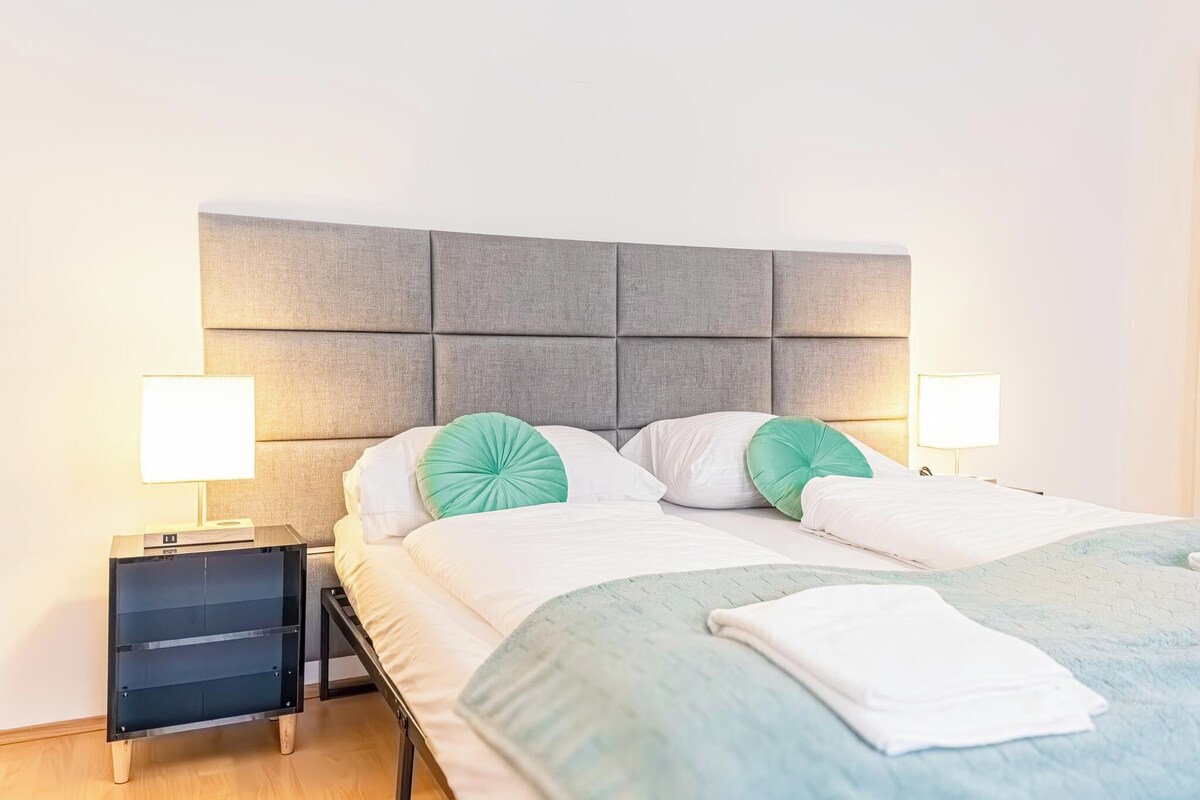 Ein Hotelzimmer mit einem Bett, zwei Nachttischen und einem Beistelltisch.