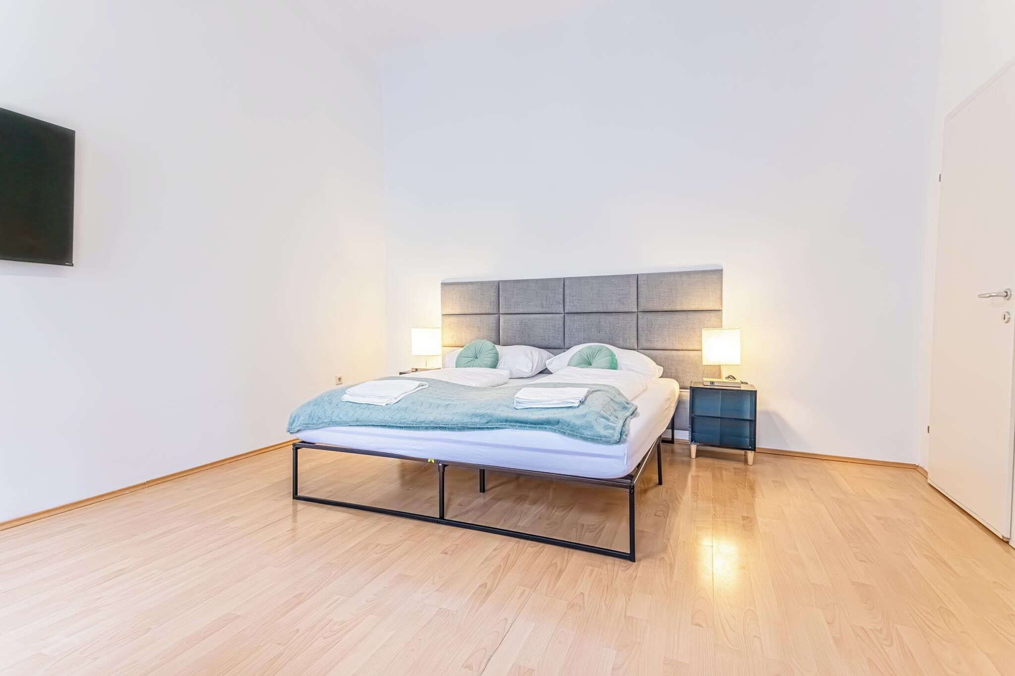 A modern bedroom with a bed, bedside tables, and a headboard.