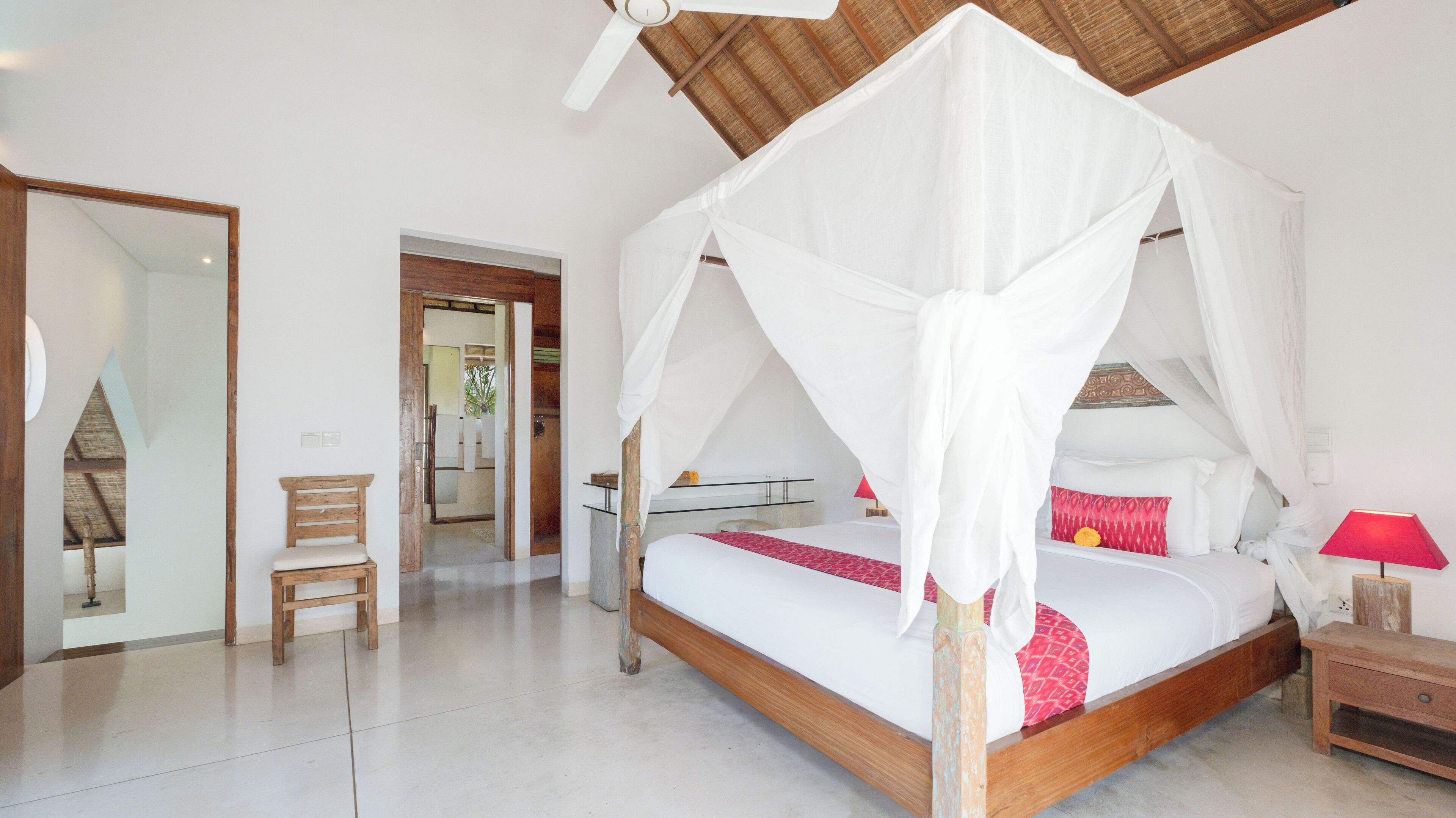 A bedroom with a four-poster bed, a wooden bench, a nightstand, and a ceiling fan.