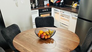Ein Essbereich mit einem runden Holztisch, vier gepolsterten Stühlen und einer Obstschale auf dem Tisch.