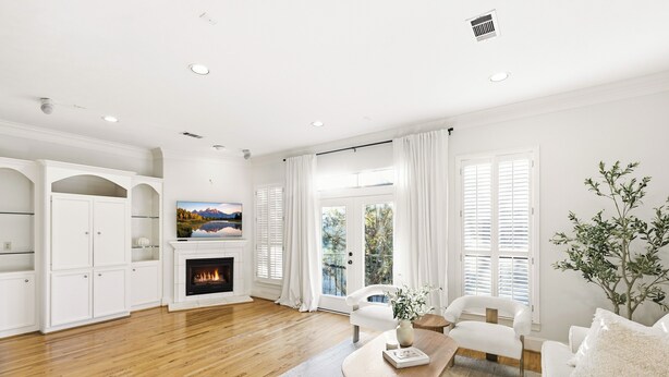 Una sala de estar moderna con chimenea, muebles blancos y vistas amplias a través de grandes ventanales.