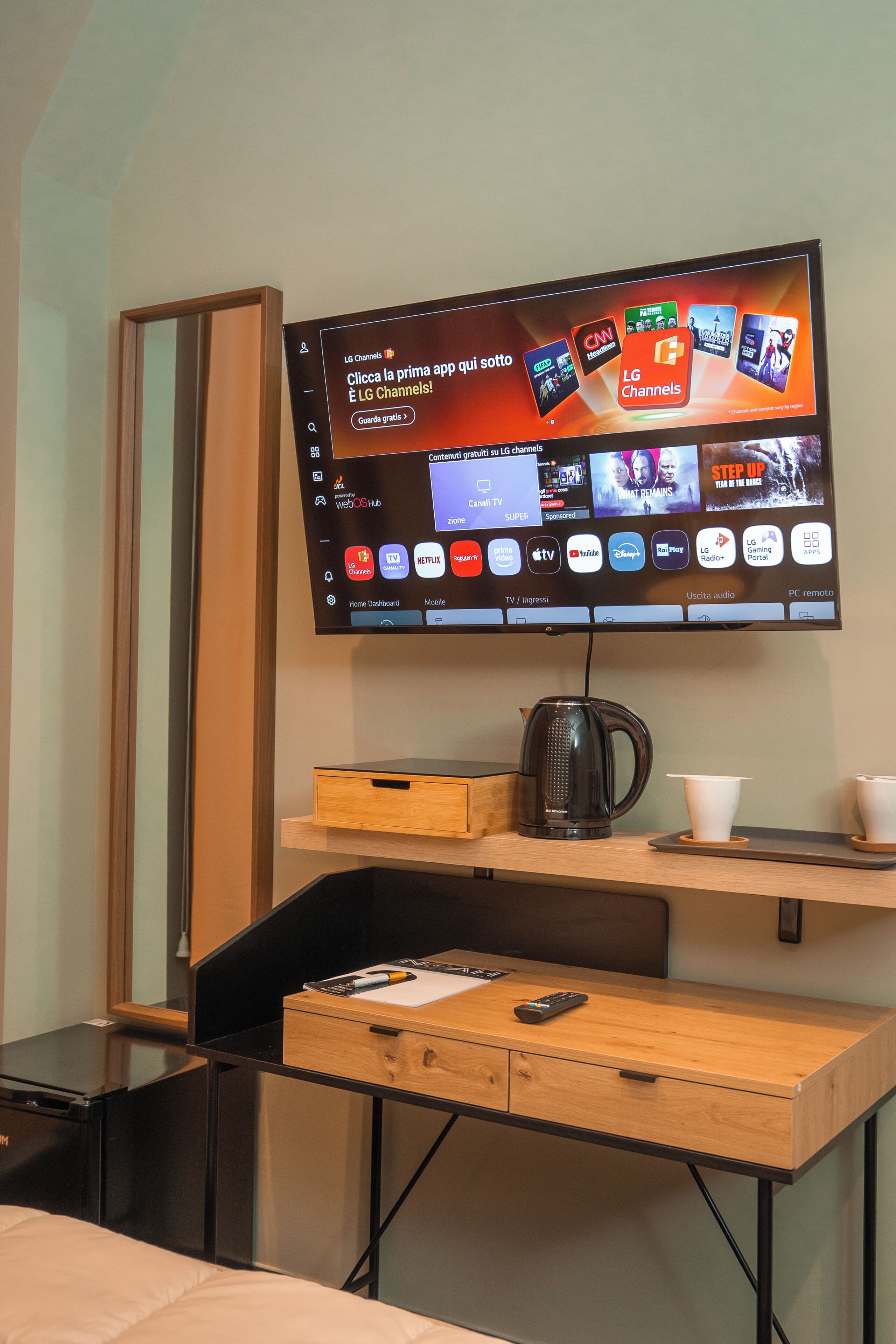 A flat-screen TV mounted on a wall displaying various streaming services and channels.